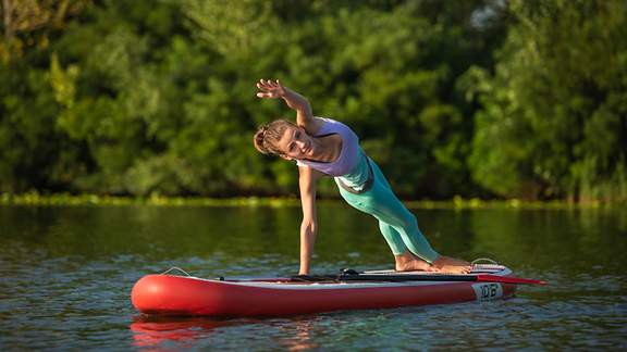 Junge Frau macht Yoga auf dem SUP Board