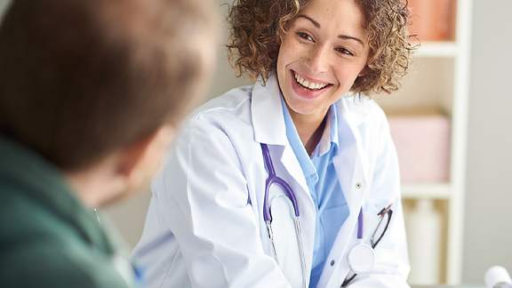 Krankenvollversicherung, Mein Privatschutz, GesundProMed, GesundProMedP: Lächelnde Ärztin in einem Gespräch mit ihrem Patienten 