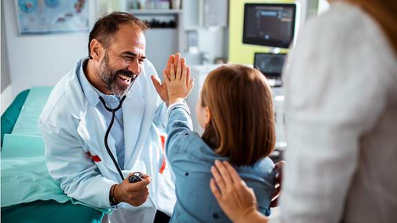 Krankenhauszusatzversicherung: Arzt und Mädchen machen high five