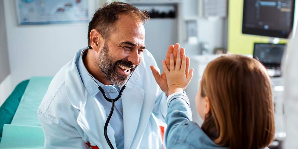Krankenhauszusatzversicherung: Arzt und Mädchen machen high five