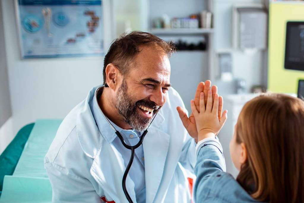 Krankenhauszusatzversicherung: Arzt und Mädchen machen high five