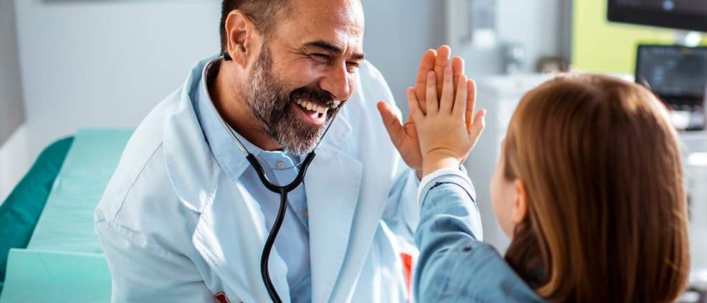 Krankenhauszusatzversicherung: Arzt und Mädchen machen high five