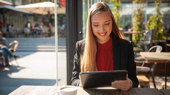 Frau sitzt in einem Café an ihrem Laptop