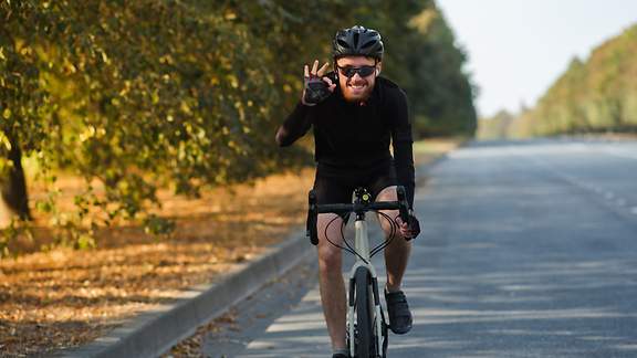 Ein junger Mann mit Brille fährt auf dem Fahrrad