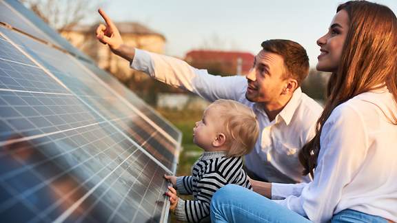 Ein Mann zeigt seiner Frau und seinem Kind eine Photovoltaik-Anlage