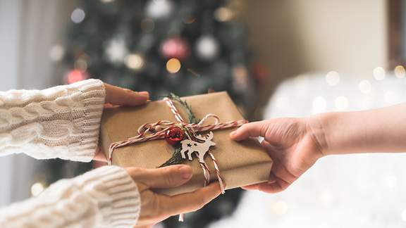 Geschenkübergabe vor dem Weihnachtsbaum