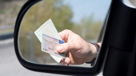 Spiegelung eines Führerscheins im Seitenspiegel eines Autos