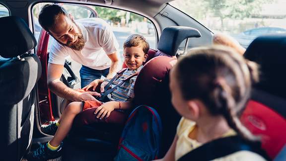 Vater sorgt sich um die Sicherheit seiner Kinder vor einer Autofahrt.