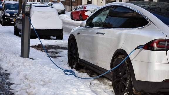 Ein Elektroauto lädt seine Akkus an einer verschneiten Aufladestation auf.