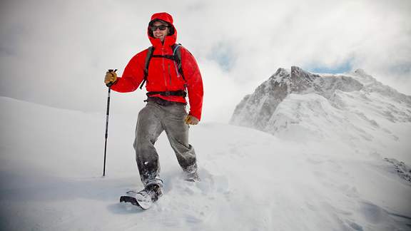 Mann in roter Jacke beim Schneeschuhwandern