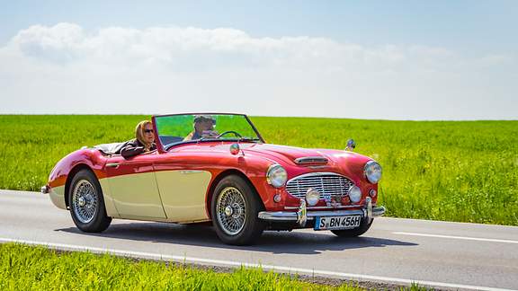 Altes Ehepaar fährt im Oldtimer durch die Landschaft