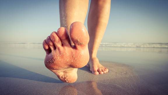 Nackter Fuß vor dem Aufsetzen im Sand