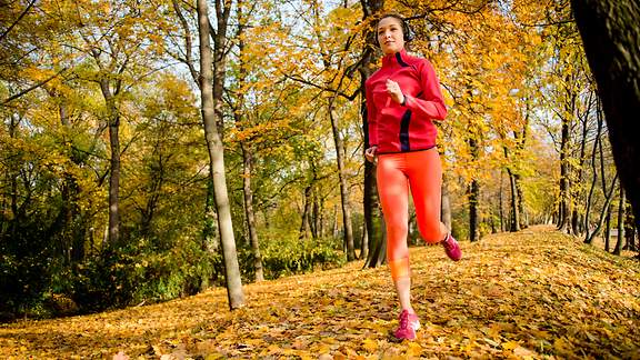 Frau joggt durch einen herbstverfärbten Park