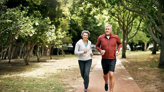 Ein älterer Mann und eine ältere Frau joggen durch den Park