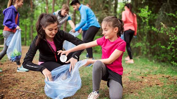 Jugendliche sammeln Müll im Wald ein