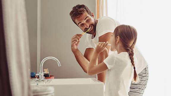 Vater und Tochter putzen gemeinsam ihre Zähne