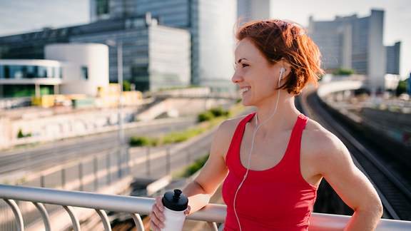 Eine Joggerin macht eine Trinkpause auf einer Brücke