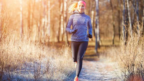 Eine junge Frau joggt durch den winterlichen Wald