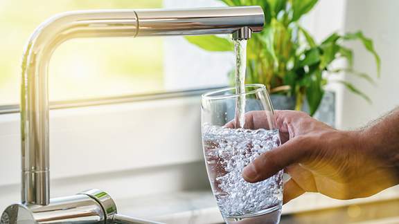 Ein Mann füllt Leitungswasser in ein Glas