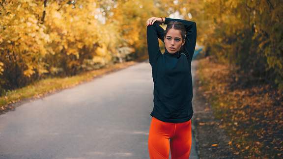 Eine junge Frau in Sportkleidung dehnt ihren Körper