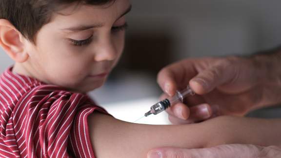 Ein Junge wird von einem Arzt geimpft.