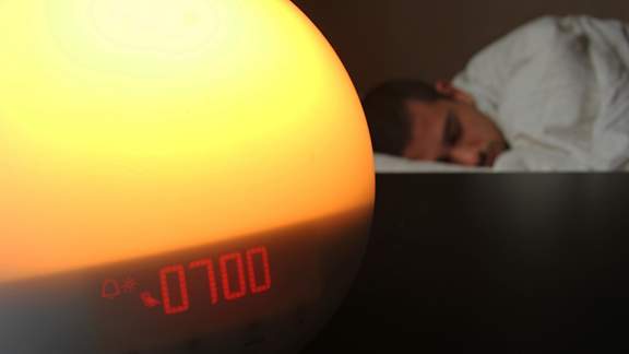 Ein Mann schläft neben einem beleuchteten Digitalwecker