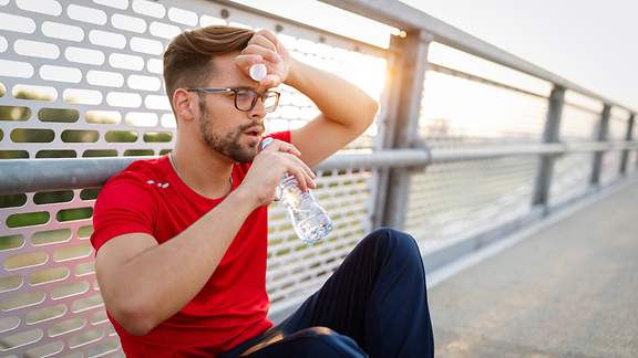 Erschöpfter Sportler macht eine Trinkpause