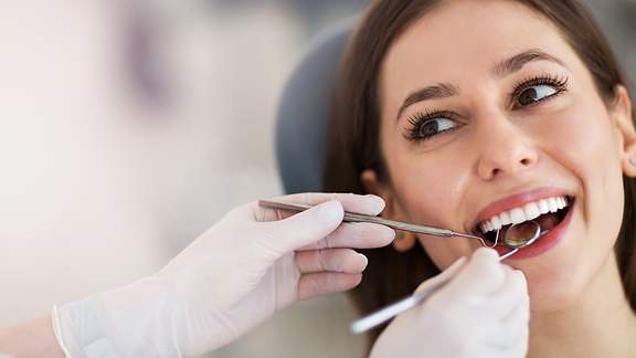 Eine Frau sitzt beim Zahnarzt auf dem Behandlungsstuhl