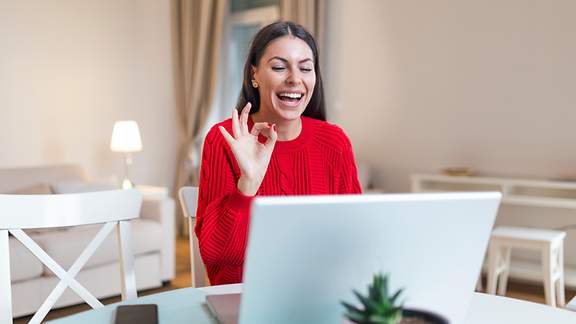 Eine Frau gestikuliert während einer Videokonferenz vor dem heimischen Computer