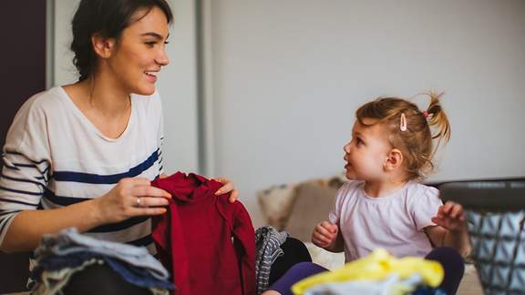 Mutter und Tochter räumen Kleiderschrank auf und trennen sich von unwichtigen Kleidungsstücken.