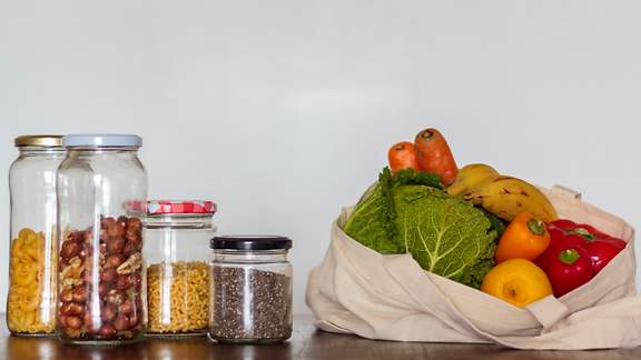Lebensmittel in Gläsern und wiederverwendbare Tasche gefüllt mit Lebensmitteln.