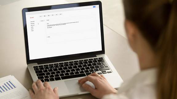 Eine Frau tippt eine E-Mail auf ihrem Laptop.