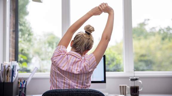 Frau streckt sich am Arbeitsplatz.
