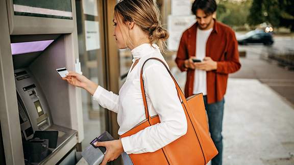 Eine junge Frau überprüft ihren Kontostand am Geldautomnaten