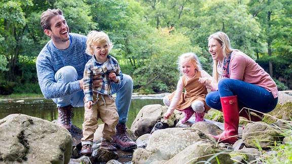 Eine glückliche Familie macht eine Pause auf Felsen während eines Wanderausfluges.