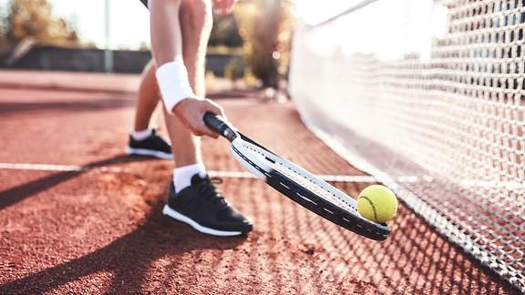 Tennisspieler habt am Netz den Ball mit seinem Schläger auf