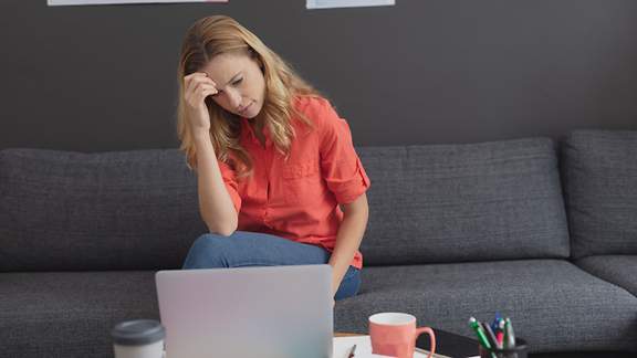 Frau sitzt verzweifelt vor ihrem Laptop