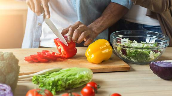 Ein Koch schneidet Paprika für einen Salat mit dem Messer
