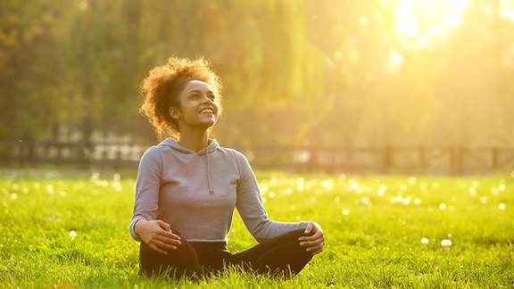 Glückliche junge Frau sitzt in Yoga-Position