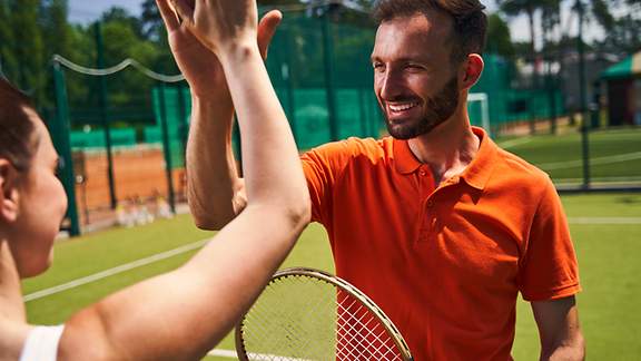 Mann und Frau klatschen sich auf dem Tennisplatz ab