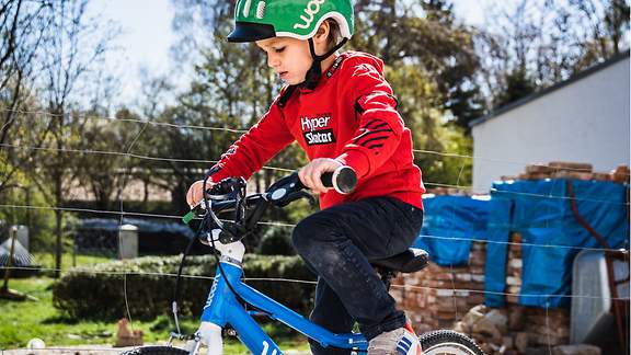 Junge mit Sturzhelm fährt auf seinem Fahrrad