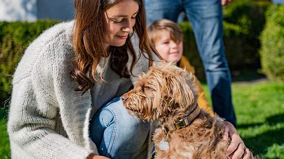 Frau kniet neben ihrem Kind und ihrem Hund