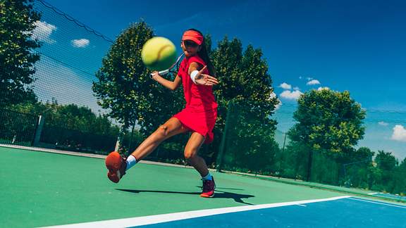 Junge Tennisspielerin holt zur Vorhand aus