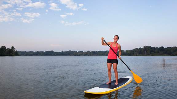 Eine Frau im roten Shirt beim Standup Paddling