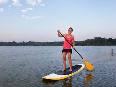 Eine Frau im roten Shirt beim Standup Paddling