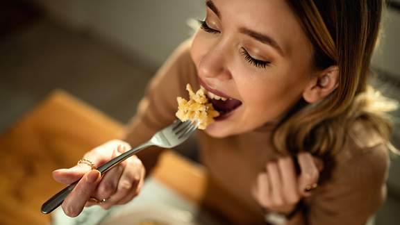 Eine Frau isst genussvoll ein Pasta-Gericht
