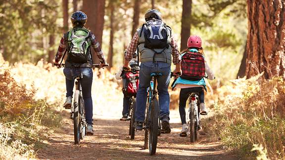 Eine Familie fährt mit dem Fahrrad durch einen Wald