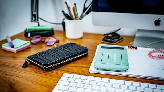 Ein Schreibtisch mit Tastatur, Taschenrechner und anderen Büromaterialien