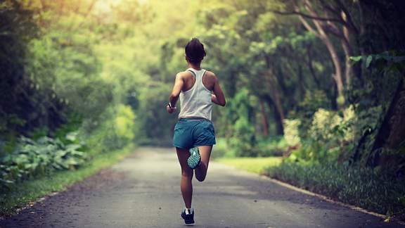 Eine Joggerin, von hinten fotografiert, läuft durch einen Park