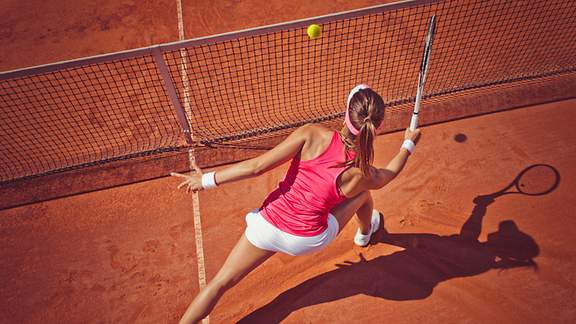 Eine Tennisspielerin macht einen Ausfallschritt am Netz